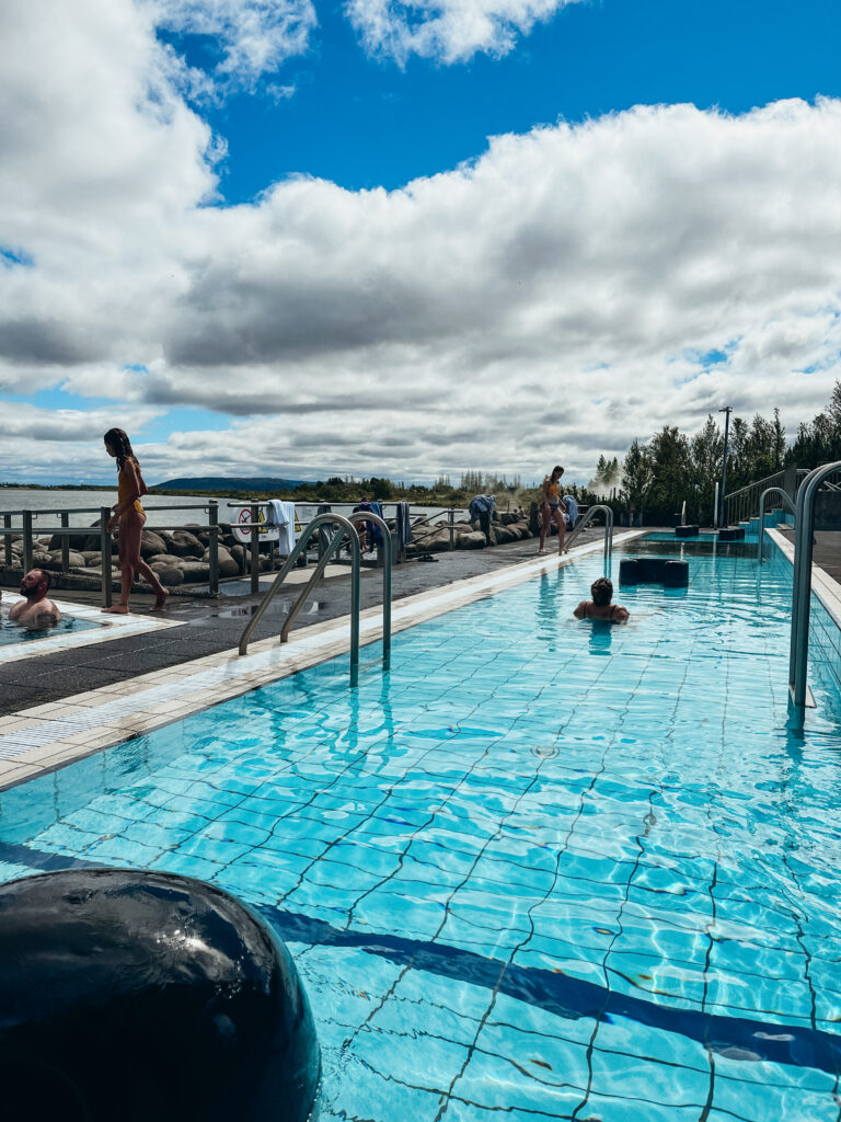 A long pool at Laugarvatn Fontana is filled with a few sunbathers enjoying the lake and bright blue skies.