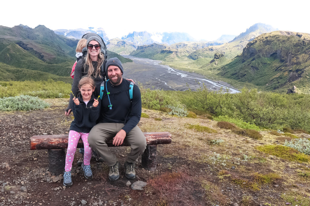 A family pauses to smile on one of their kid-friendly hikes in Iceland with the Thorsmork vista in the background.