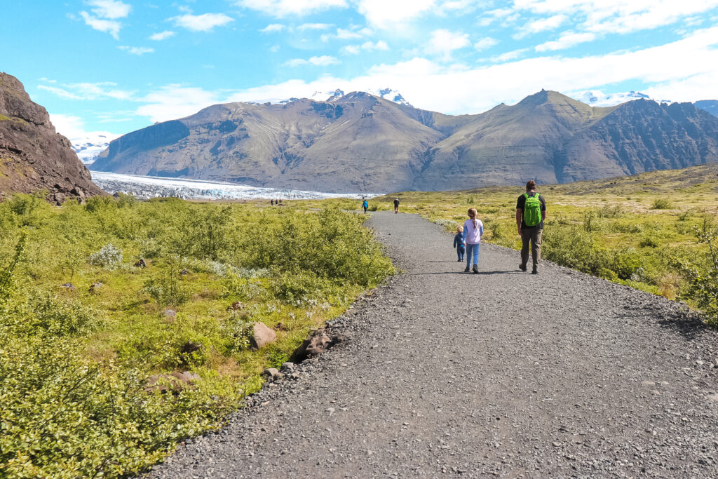 Two young children and their father go on a kid-friendly hike in Iceland twoards the Skaftafellsjokull Glacier.