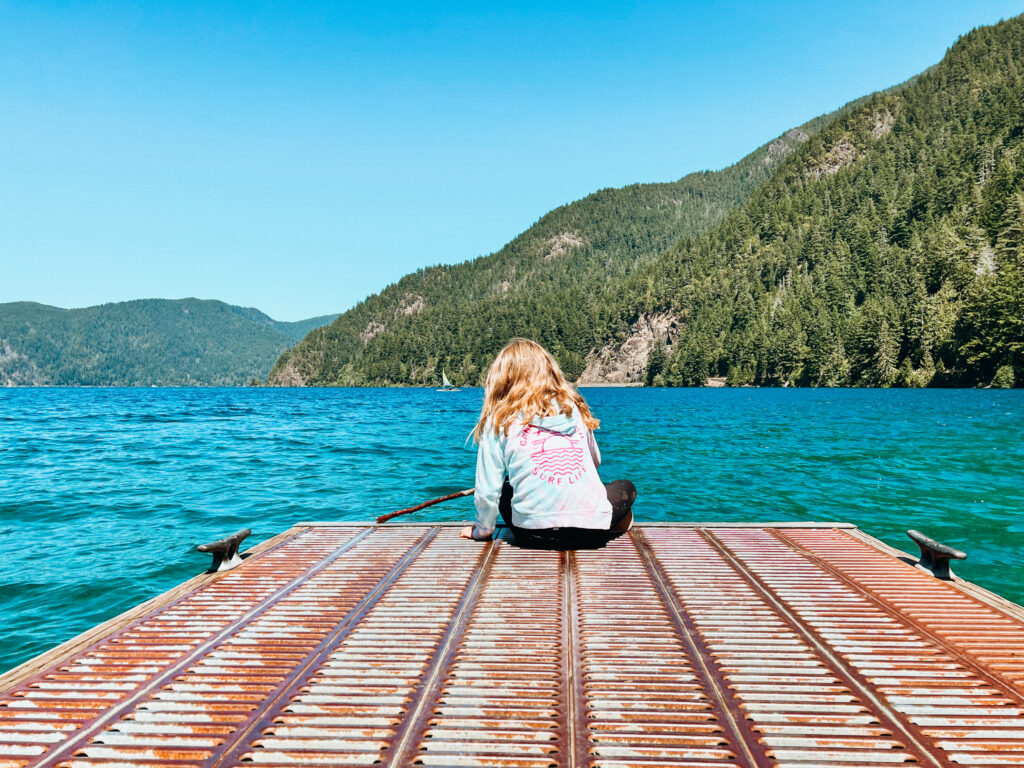 A young girl looks at the crystal clear waters of Lake Crescent, one of the best Olympic National Park hikes for families.