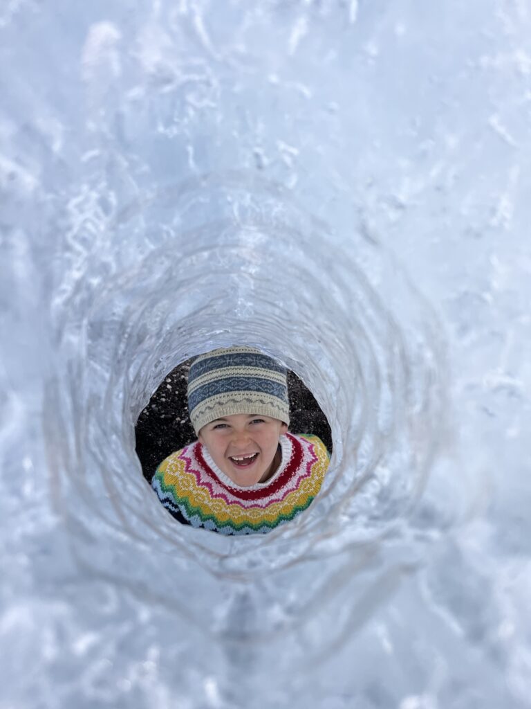 A young girl smiles through an ice tunnel on Diamond Beach in Iceland.