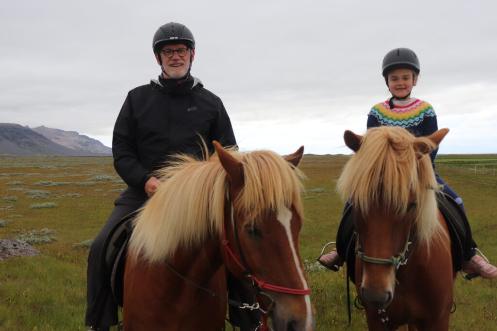 A older man and young girl sit atop Icelandic horses.