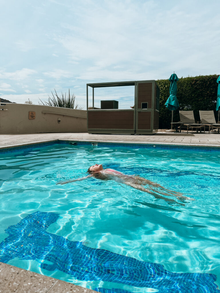 A young girl floating in a pool in Scottsdale, Arizona in a pink bathing suit.