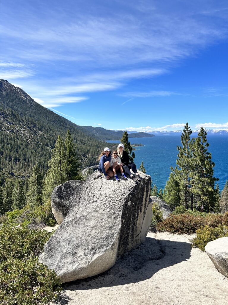 Travel mom Bernice on a rock overlooking a lake with her two young children.