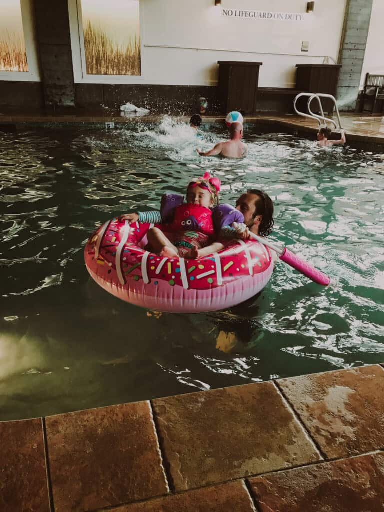 A young girl sits in a pink donut inflatable in the indoor pool at the Hallmark Resort Cannon Beach.